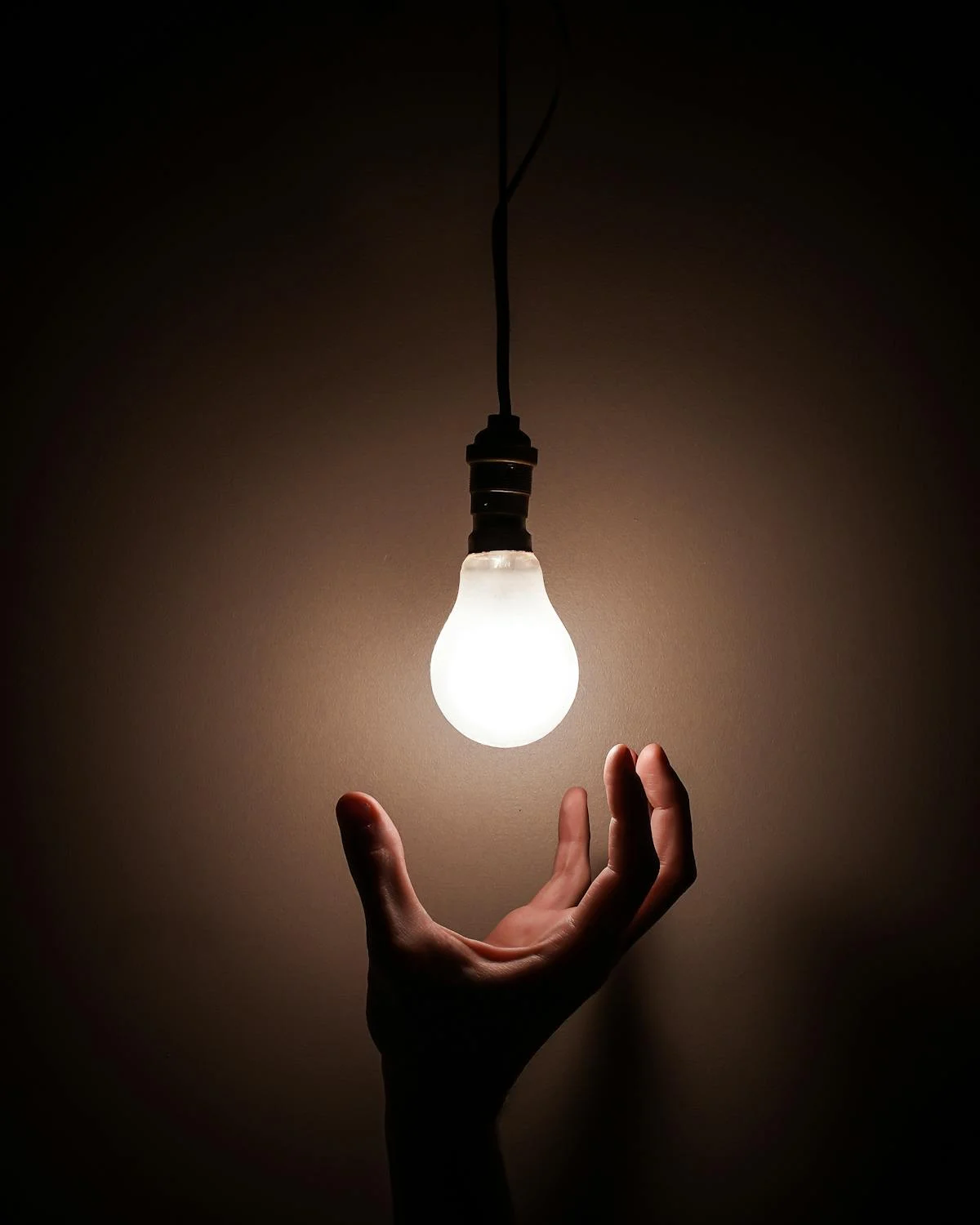 "Close-up image of a light bulb glowing softly, showing the glass bulb, filament, and metal base."